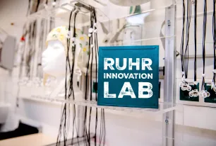 Blaues Schild mit weißer Schrift 'RUHR INNOVATION LAB' in einem Labor