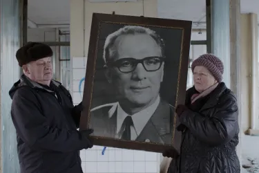 Zwei Menschen präsentieren riesiges Porträt von Erich Honecker